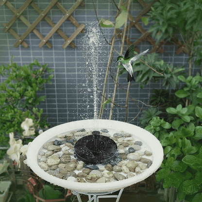 Solar-powered water fountain pump operating in birdbath surrounded by decorative stones