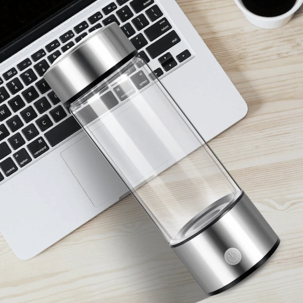 Transparent hydrogen water bottle placed beside a laptop, showcasing sleek and portable design for daily use